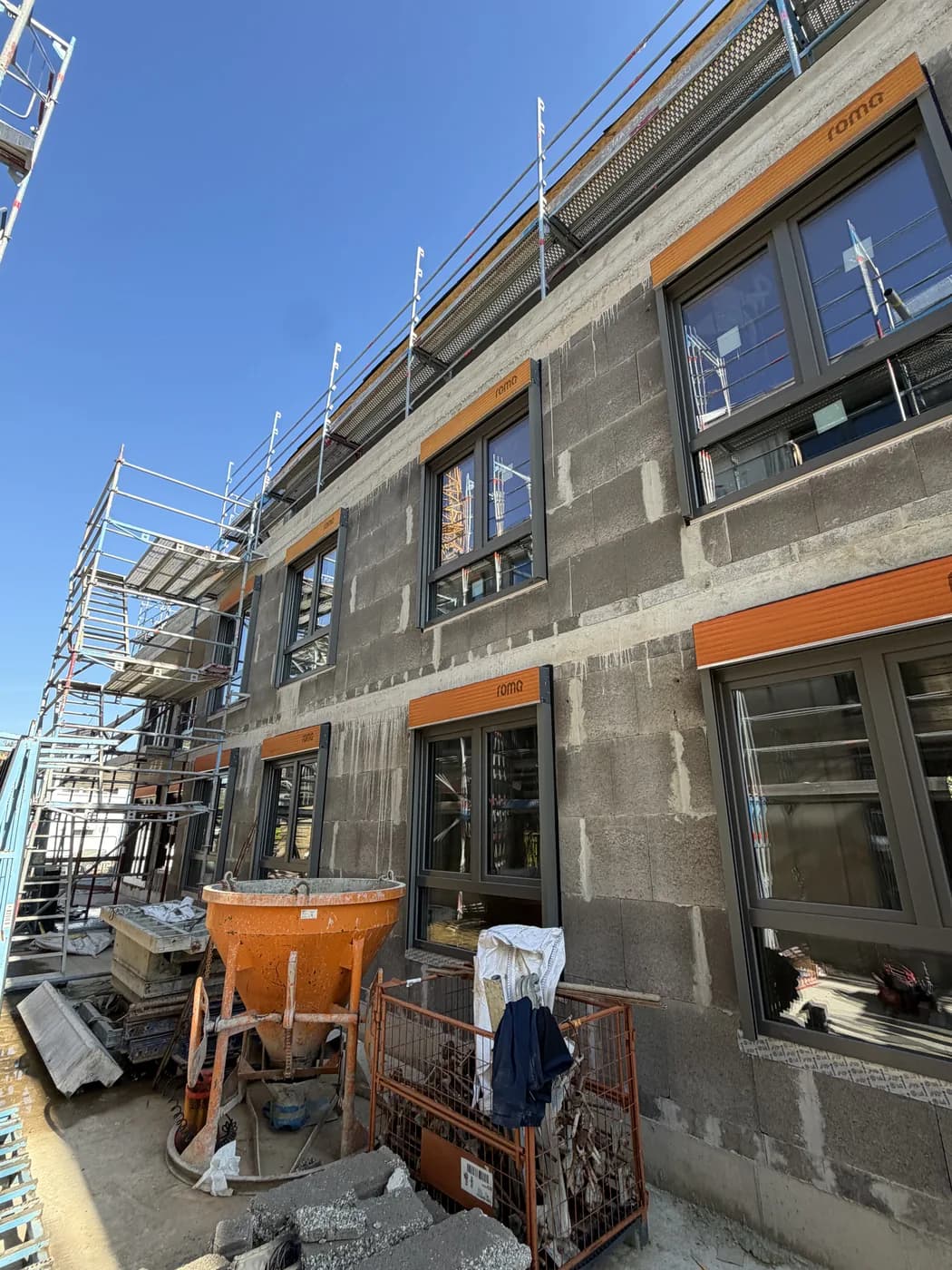 Neubau im Rohbau mit eingebauten anthrazitgrauen Fenstern und Gerüst